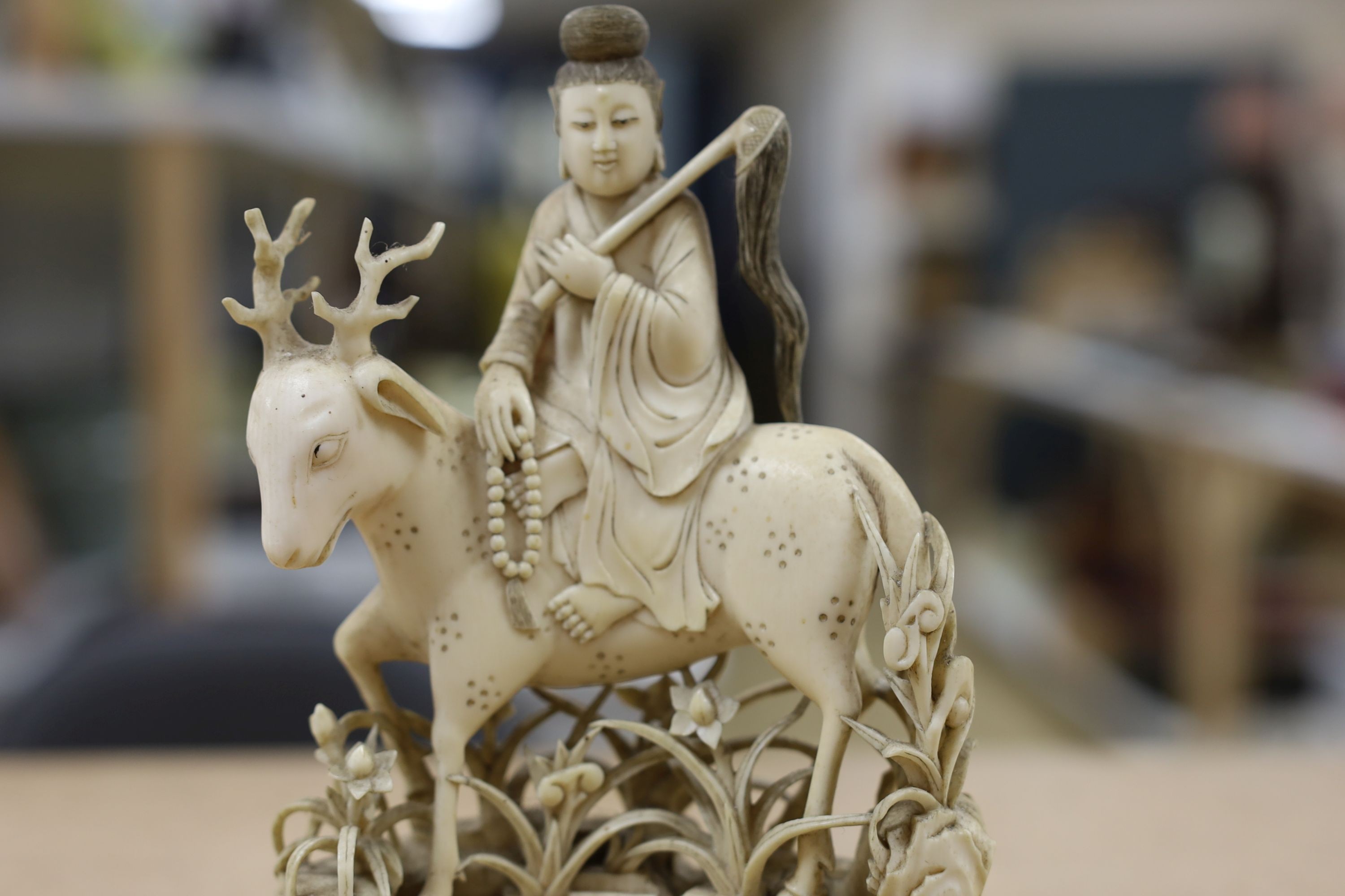A Chinese carved ivory figure of a female immortal riding a deer, early 20th century, height 17cm excl. stand